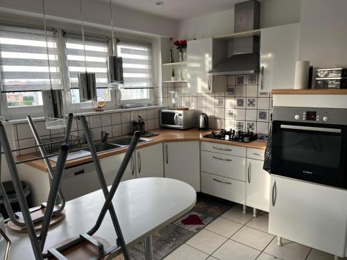 une cuisine avec des placards blancs, une table et une télévision dans l'établissement Travel homes spacieux et paisible parking privé, à Illzach