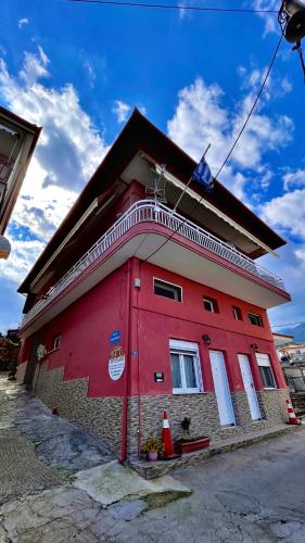 a red building with a roof on a street at Olympiades Rooms Litóchoro in Litochoro