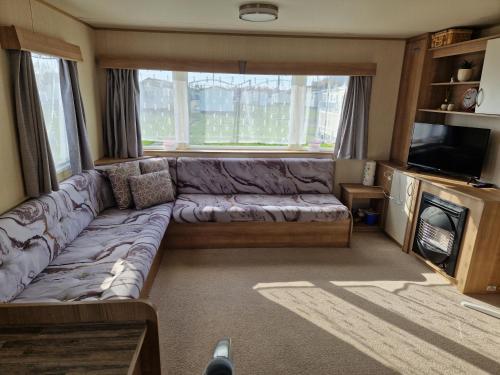 ein Wohnzimmer mit einem Sofa und einem TV in der Unterkunft Woods caravan in Ingoldmells