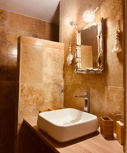 une salle de bain avec un lavabo blanc et un miroir dans l'établissement L’appart de la Plage, à Saintes-Maries-de-la-Mer