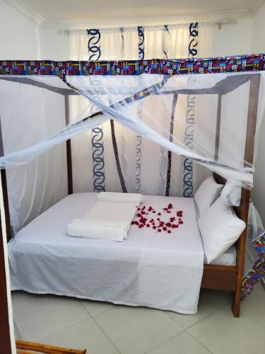 a bed with a canopy with red roses on it at Nungwi 14 bnb in Nungwi