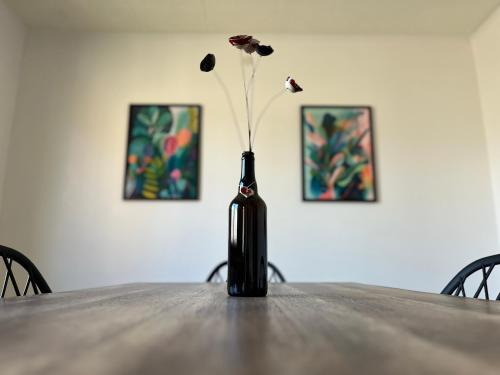 La Terasse des Vignes - Maison 2 Chambres - 4 Personnes في Blienschwiller: مزهرية سوداء مع وردة على طاولة