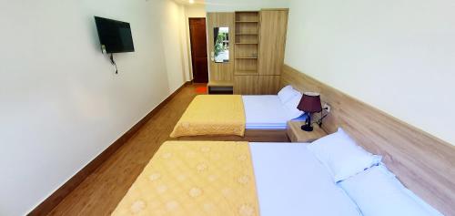 a hotel room with two beds and a tv at Khách Sạn Hoàng Nam-Cửa Lò-Nghệ An in Thương Xà (2)