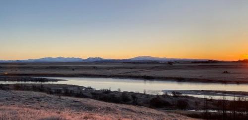 a sunset in the middle of a field with a river at Ugla Gistihús (Ugla Guesthouse) in Hella