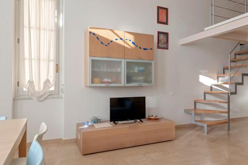 a living room with a tv and a staircase at Luminosity by the sea in Calambrone