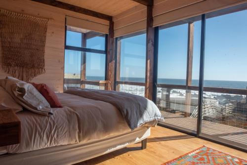 a bedroom with a bed with a view of the ocean at Espectacular Casa Palafito frente al mar in Pichilemu