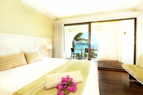 a bedroom with a bed and a view of the ocean at Holland House Beach Hotel in Philipsburg