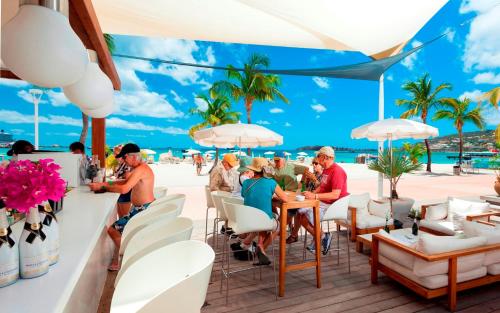 people sitting at a table with umbrellas at Holland House Beach Hotel in Philipsburg