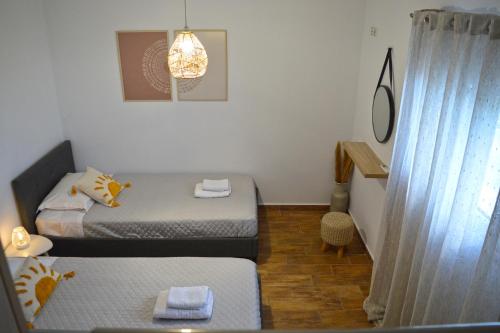 um pequeno quarto com 2 camas e uma janela em SunShine House em Ermoupoli