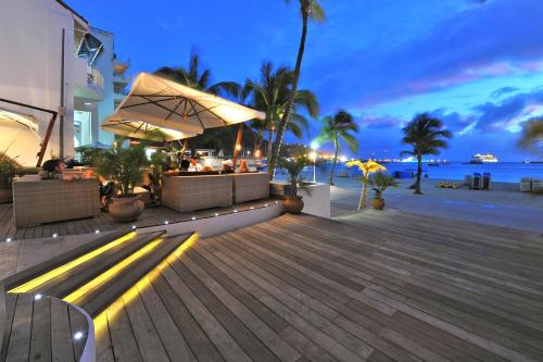 a deck with a bar on the beach at night at Holland House Beach Hotel in Philipsburg