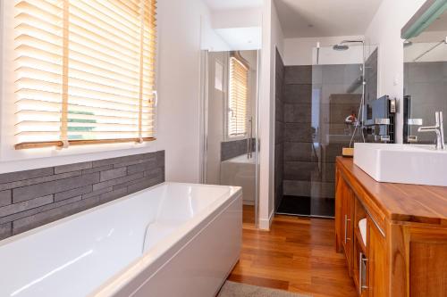 une salle de bain avec une baignoire blanche et un lavabo dans l'établissement Villa Kate, Villa moderne, 5 ch. accès privé à la plage, à Grimaud