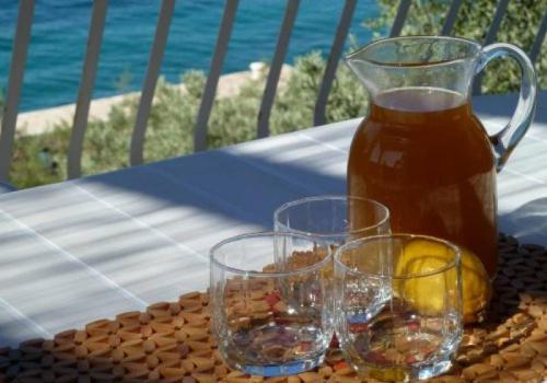 two glasses and a jug of tea on a table at Apartment Val in Kaprije