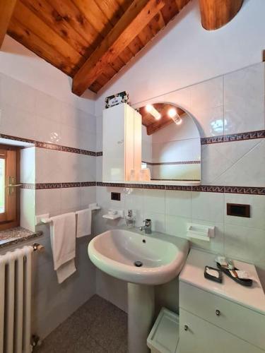 Baño blanco con lavabo y espejo en Chalet Dolce Vita, en Gerola Alta