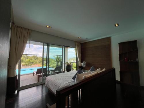 a bedroom with a bed and a view of a pool at Villa Tantawan Resort - Private Pool Villas in Kamala Beach