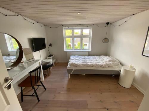 1 dormitorio con cama, escritorio y ventana en Wonderful house & garden, en Tommerup