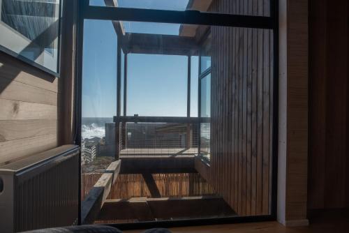 an open door to a balcony with a view of the ocean at Espectacular Casa Palafito frente al mar in Pichilemu