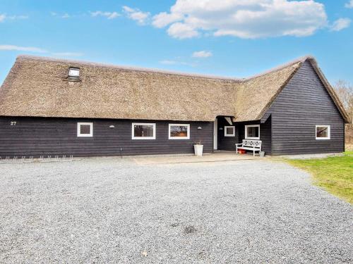 a large black barn with a grass roof at 20 person holiday home in R m in Toftum