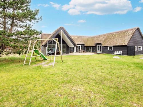a large yard with a playground in front of a house at 20 person holiday home in R m in Toftum