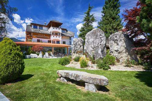 una casa grande con un banco de piedra en el patio en Mineralienhotel Natznerhof, en Naz-Sciaves