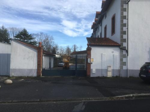a white house with a gate and a garage at Les spas de la Chartreuse in Tarbes