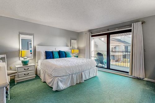 a bedroom with a bed with blue pillows and a balcony at Seawinds Oceanfront Condo in St. Augustine