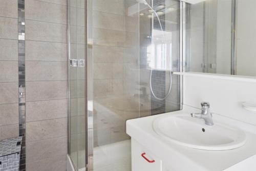 Un baño blanco con lavabo y ducha. en Résidence Jessica à Bondoufle, en Bondoufle