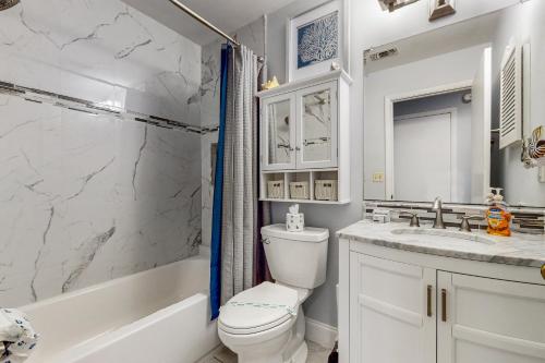 a bathroom with a toilet and a tub and a sink at Seawinds Oceanfront Condo in St. Augustine