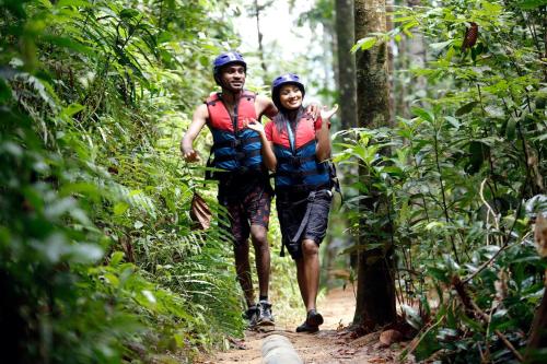 a man and woman walking down a trail in the forest at Ceylon Adventure Sports in Kitulgala