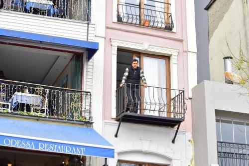 Karaköyde deniz manzaralı oda في إسطنبول: رجل يقف على شرفة مبنى