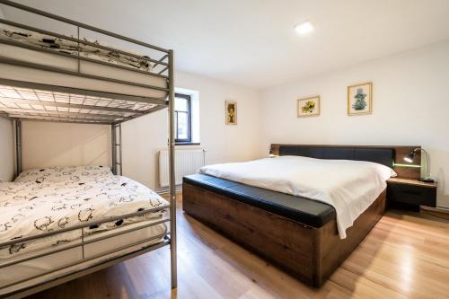 a bedroom with two bunk beds and a wooden floor at Penzion Pod hradem in Adršpach