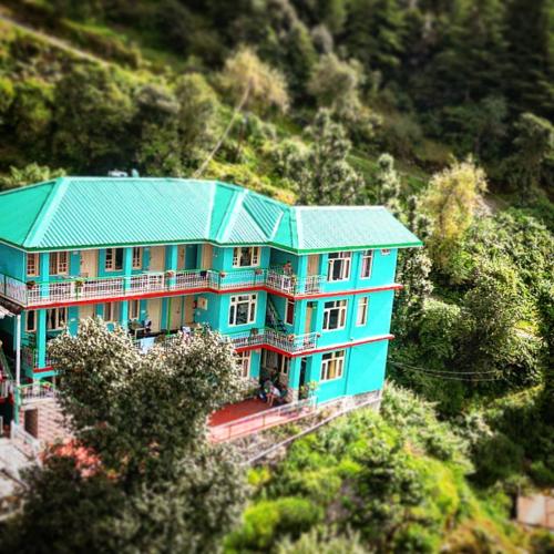 una casa azul con techo verde en una colina en Jagatram Niwas Guesthouse Dharamkot, en Dharamshala