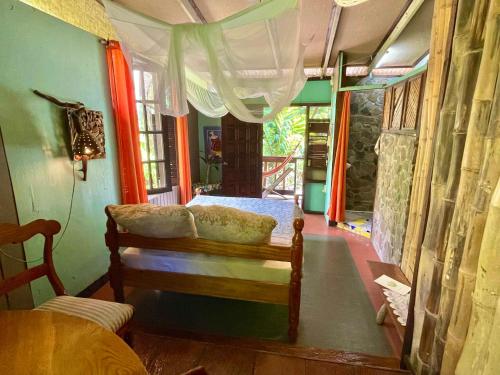 a room with a couch and a bed and a window at Cocoa Cottage in Roseau