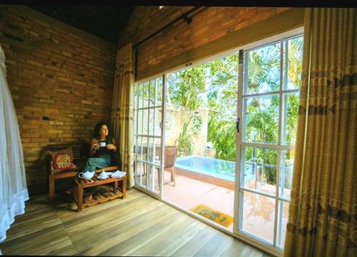 uma mulher sentada numa cadeira num quarto com uma grande janela em Airport Villa Kamatha -Foreign booking only em Katunayaka