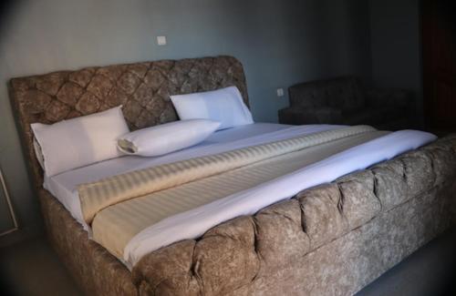 a large bed with white pillows on top of it at Zeyman’s Appartments in Kigali