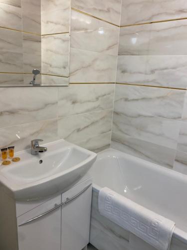biała łazienka z umywalką i wanną w obiekcie Tabago Studio 17 w Bełchatowie