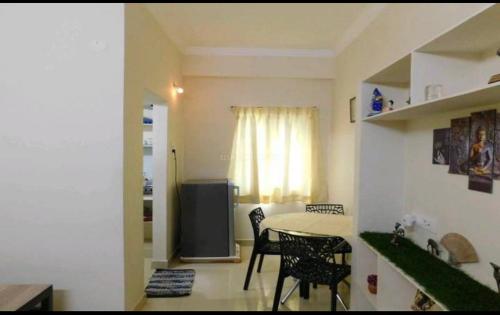 ein Wohnzimmer mit einem Tisch, Stühlen und einem Fenster in der Unterkunft Dpinn homestay in Hyderabad