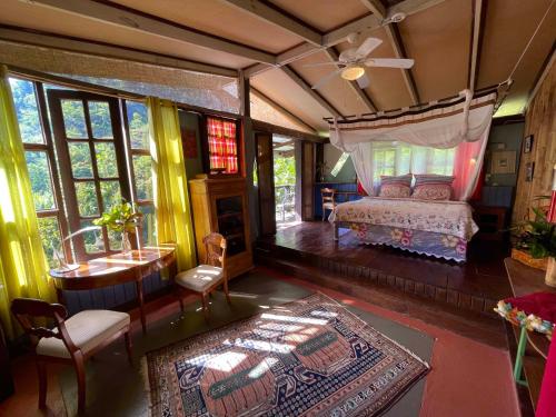 a bedroom with a bed and a table and windows at Cocoa Cottage in Roseau