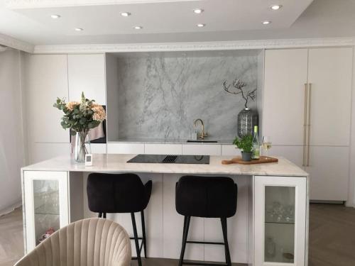 a kitchen with a counter with two chairs and a sink at Stan- och strandnära poolvilla. in Halmstad