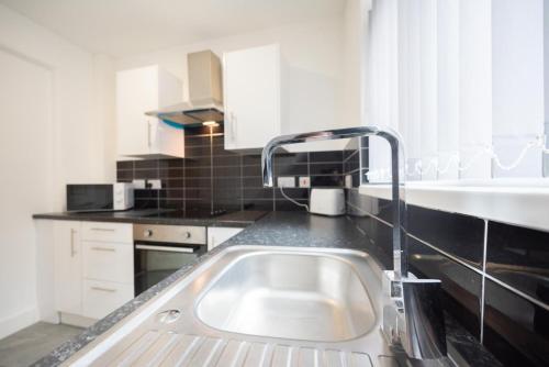 a kitchen with a sink and a faucet at Pottery House by YourStays in Stoke on Trent