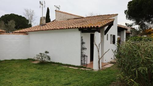 a white house with a tiled roof and a yard at La sauvagine in Saintes-Maries-de-la-Mer