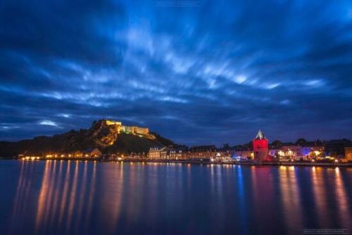 a view of a town on a hill over the water at night at Le Bellevue in Givet