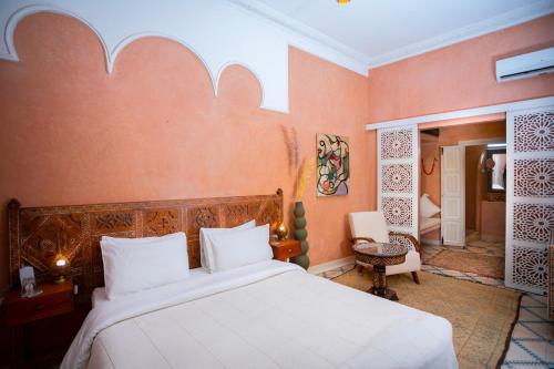 1 dormitorio con cama blanca y pared de color naranja en Riad Miss Caracal, en Marrakech