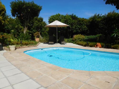 a swimming pool with an umbrella next to a patio at Garden- Pool flat with Solar Electricity in Somerset West