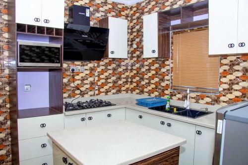 een keuken met witte kasten en een fornuis met oven bij Cozy Urban Oasis 3 Bedroom in Ogba, Ikeja, Lagos in Egba