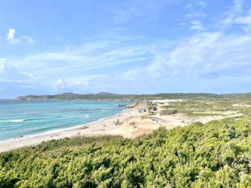 a beach with people on the sand and the ocean at Sardinia SeaBreeze Villa IUN R2178 in Castelsardo
