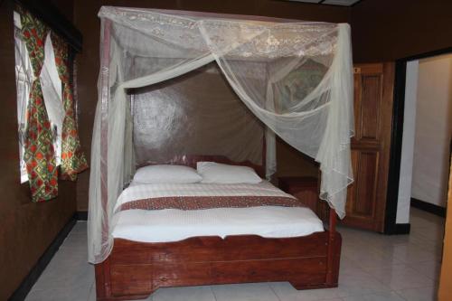 1 dormitorio con cama con dosel, sábanas y almohadas blancas en Room in BB - Amahoro Guest House - Queen Room en Ruhengeri