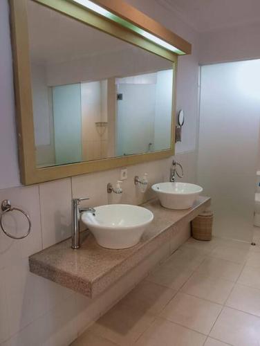 a bathroom with two sinks and a large mirror at Glisten Up Villa Beach Side Sanur! in Sanur
