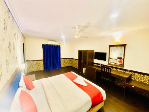 a bedroom with a bed and a desk and a television at The City Park hotel in Hyderabad