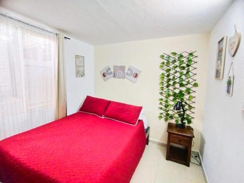 um quarto com uma cama vermelha e uma planta em Apartamento Familiar Privado 101 Con Baño Cocina Tv Wifi Sala em Salento