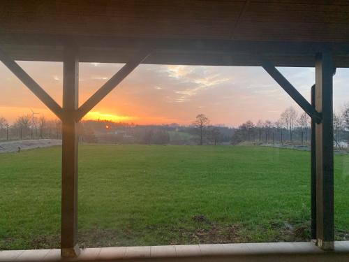 a view from a window of a field with the sunset at Żałesisko in Rypin